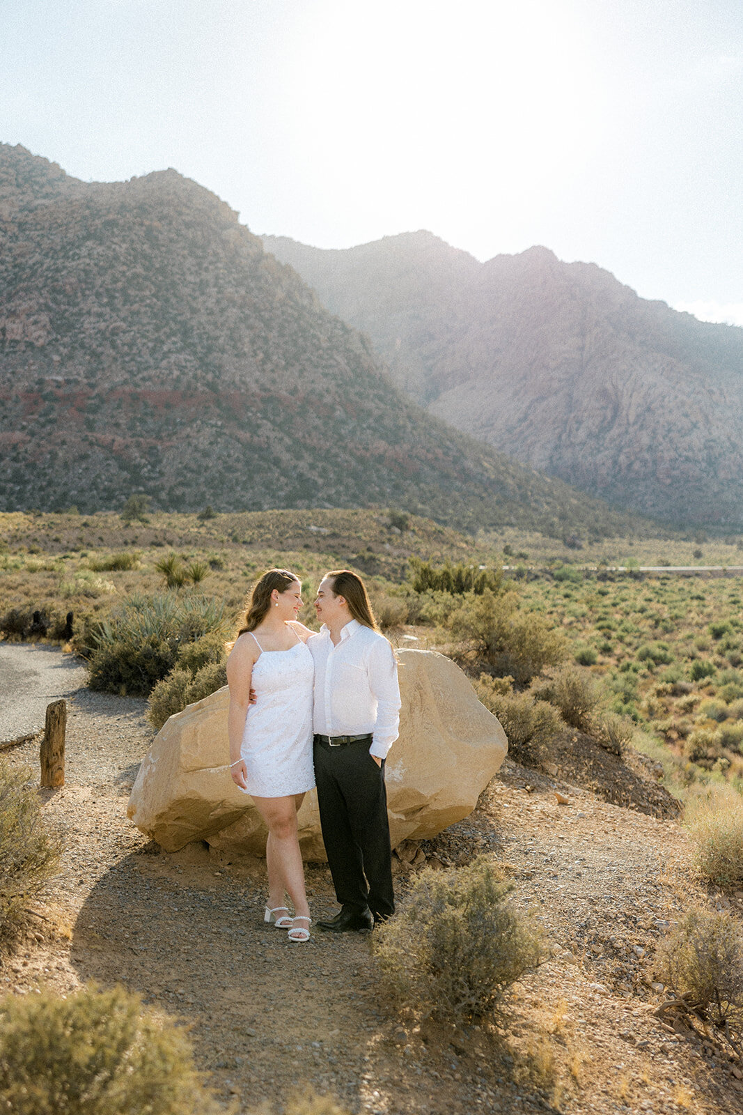 Engaged couples smiling with mountains in the background in Nevada