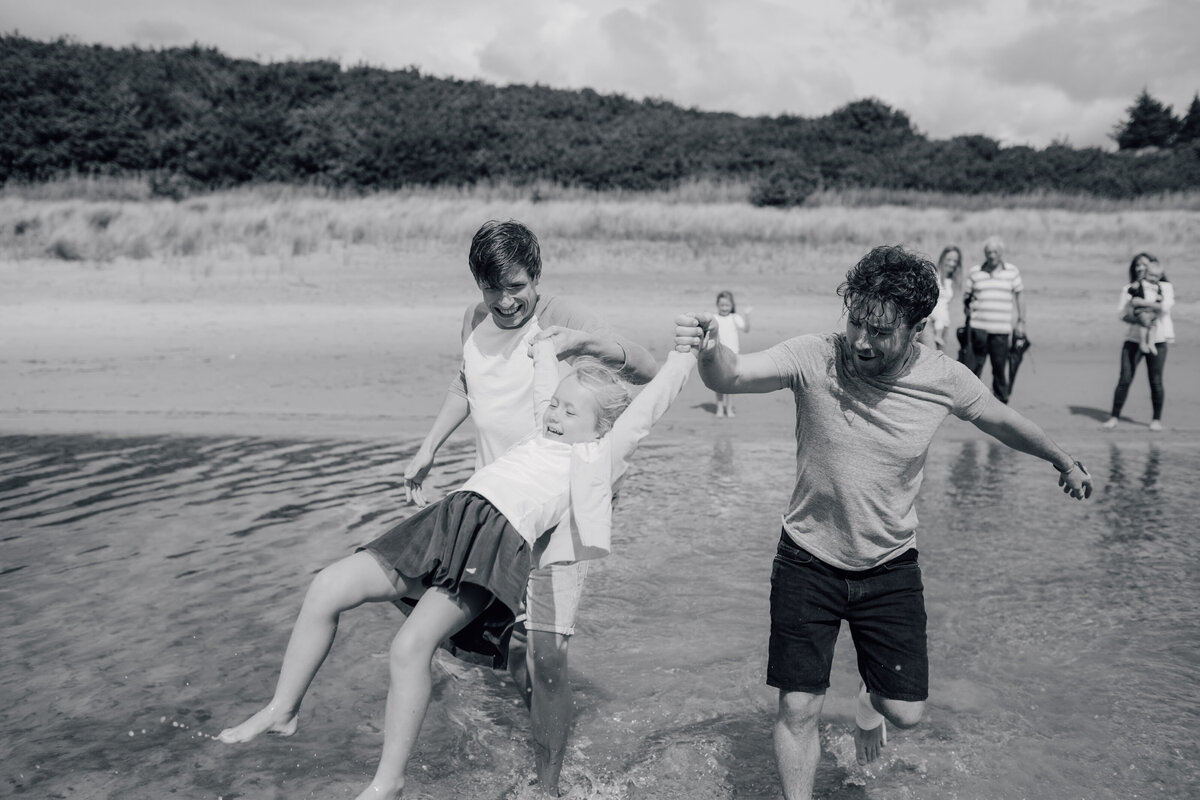 boys-swinging-little-girl-over-water-at-beach