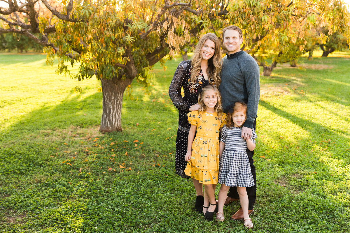 family smiling together in Gilbert orchard