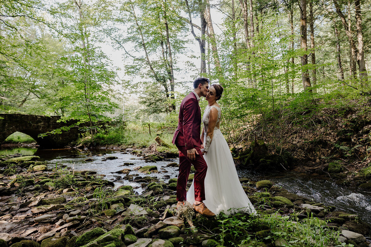 A person kissing their partner on the cheek while they stand next to a river