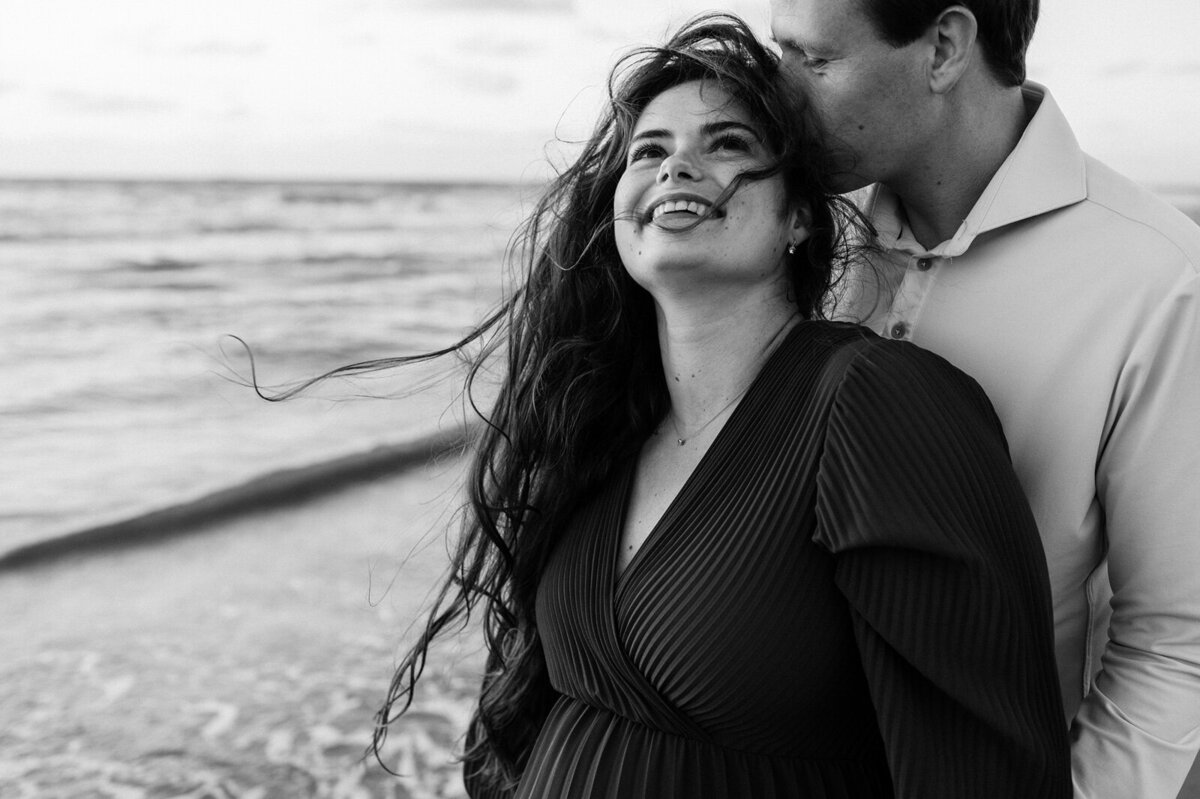 Vrouw geeft man op achterhoofd kus en vrouw moet lachen