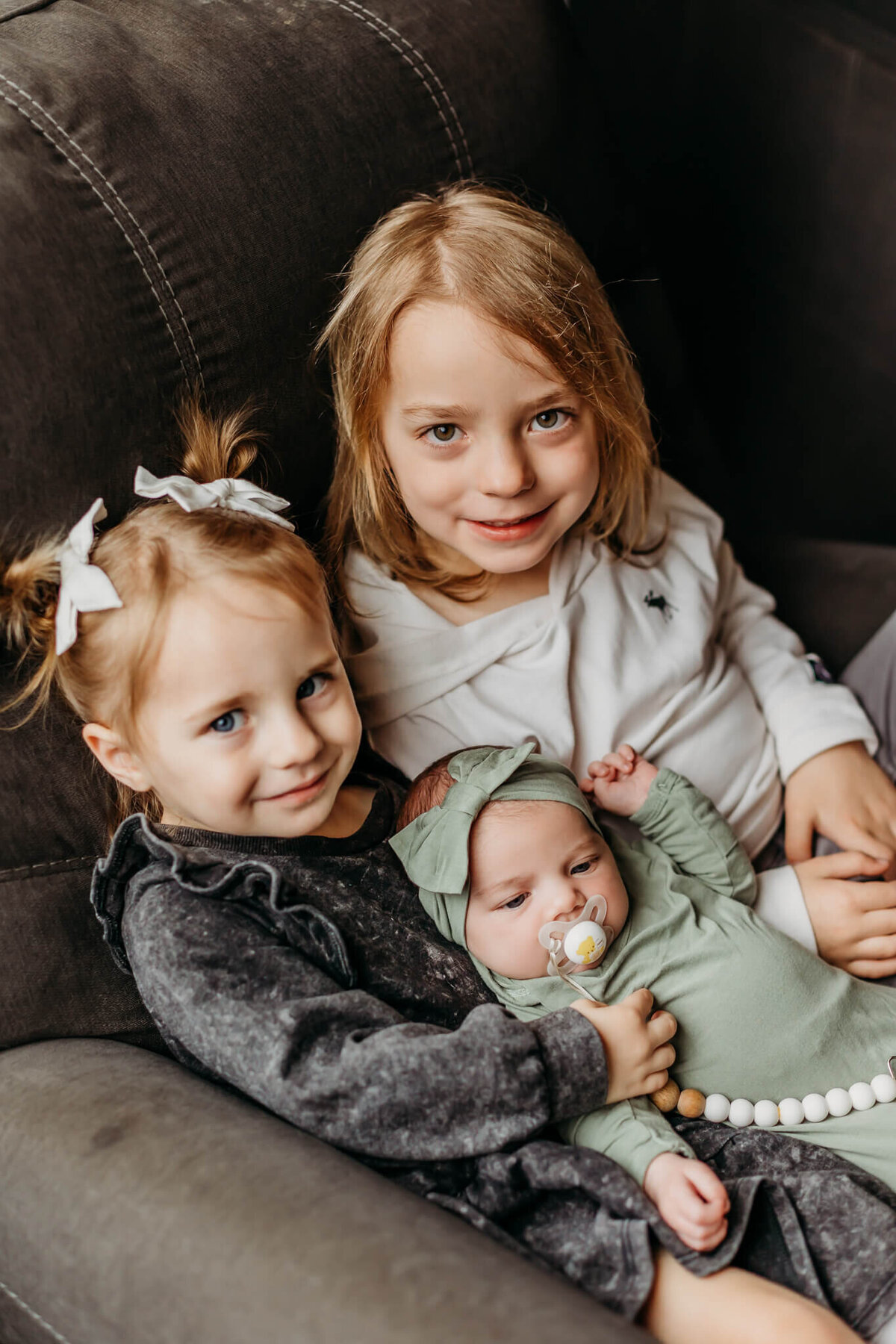 siblings holding newborn baby in their home near eau claire wi