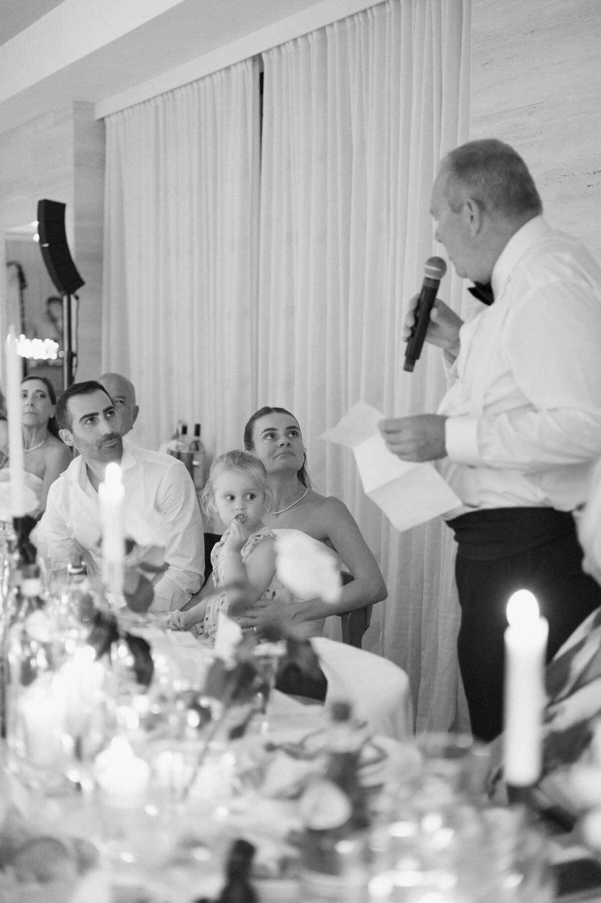 Black and white photo of candlelit wedding dinner with guests dining

