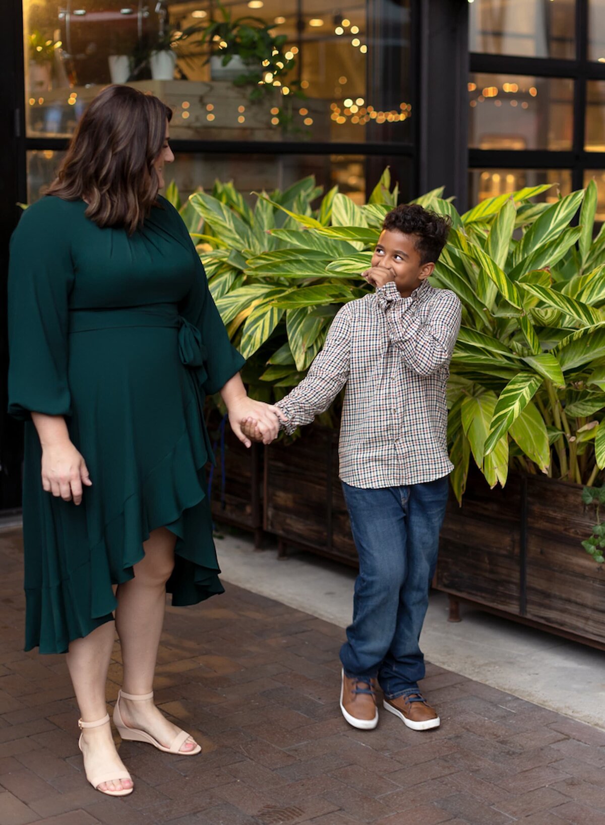 image of a boy wearing plaid shirt smiling and looking at his mom wearing a green dress.