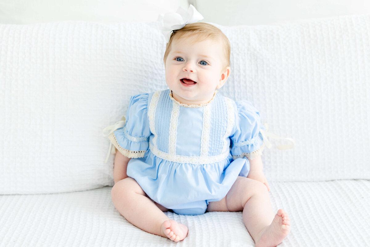 Baby sitting up looking off camera smiling for milestone photography