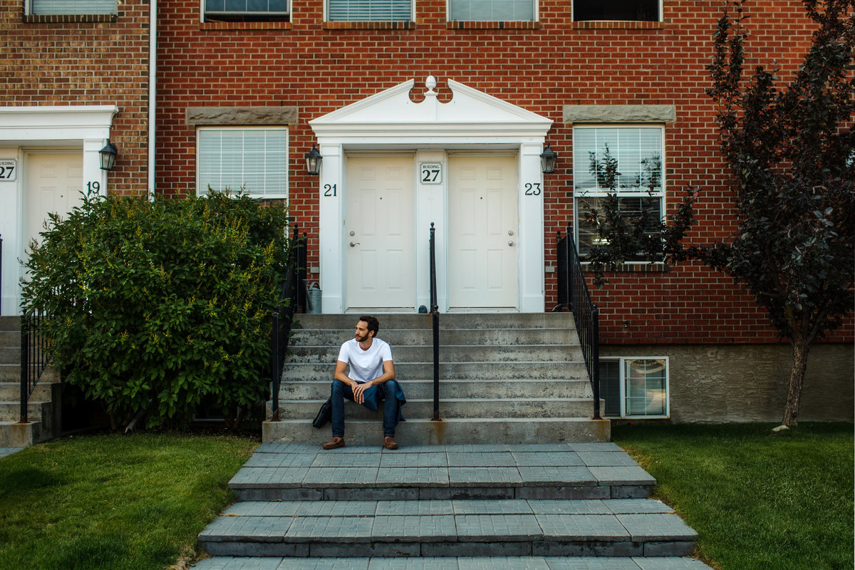 Man sitting on steps of a brownstone