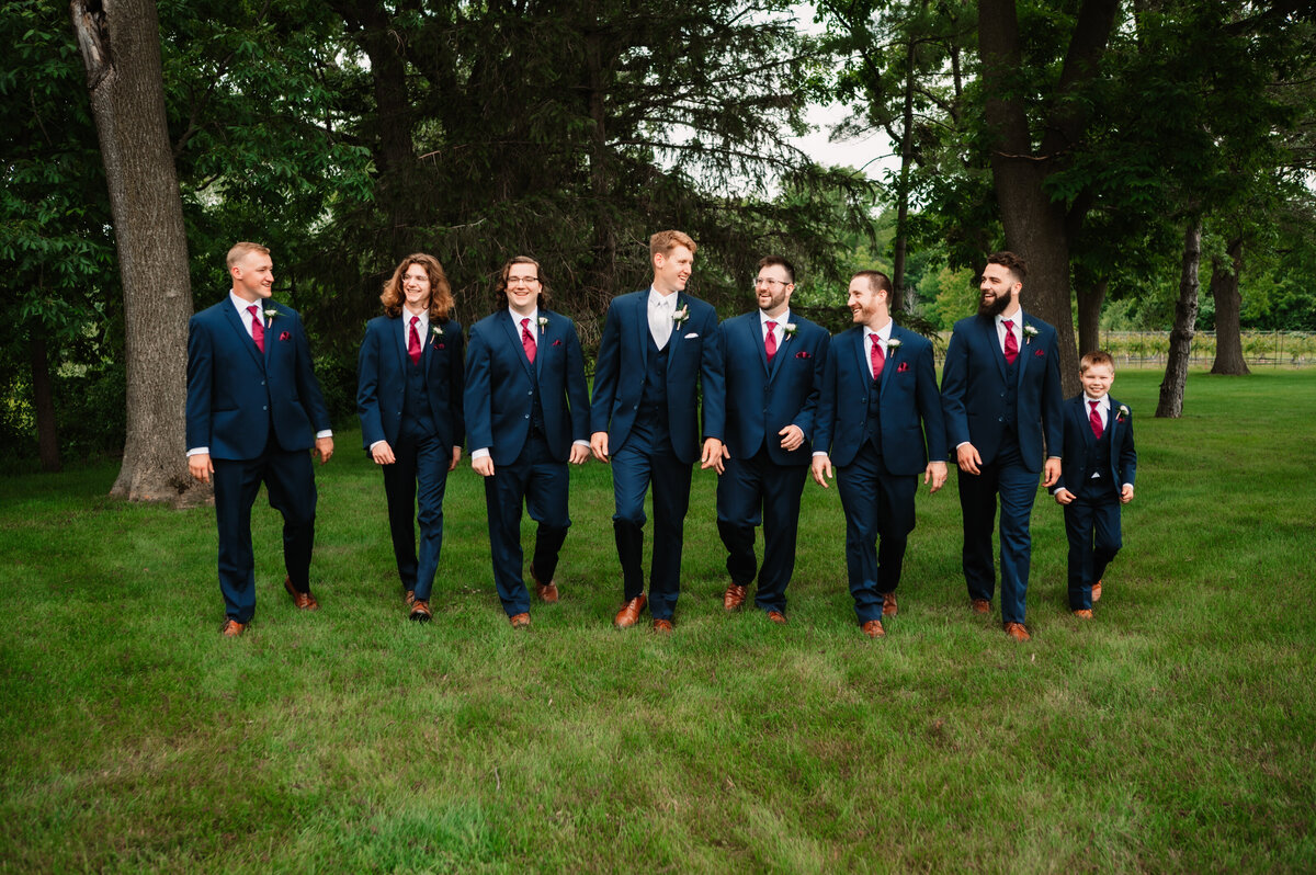 A groom walks with his groomsmen in a lawn in all blue suits