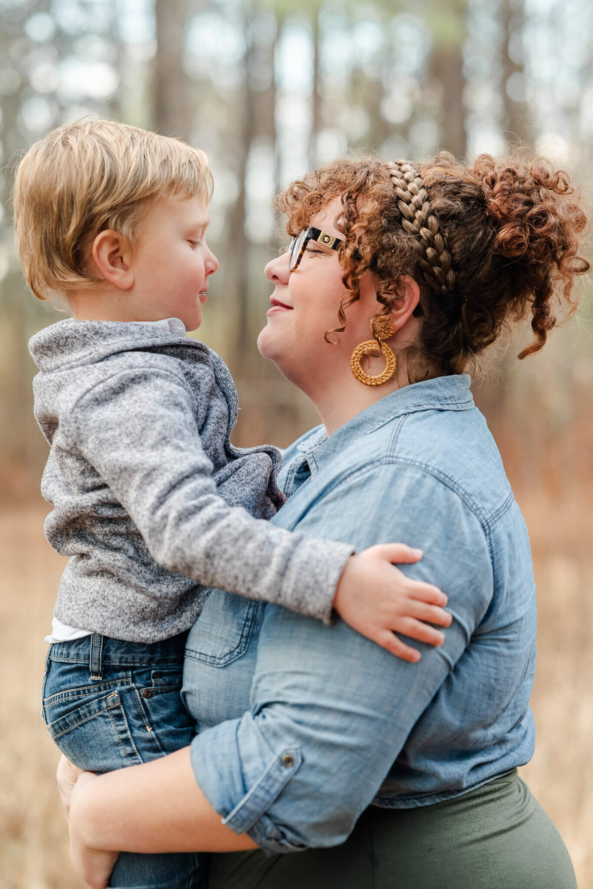 A mother holds her young son during their Virginia Beach family photography session. They look into each other's eyes and smile.