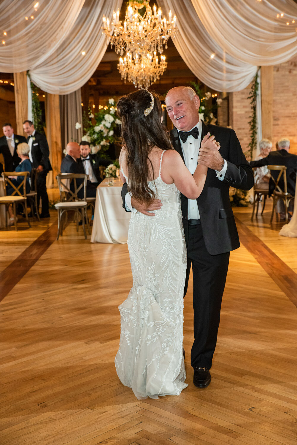 A man in a tuxedo is dancing with a woman in a white dress