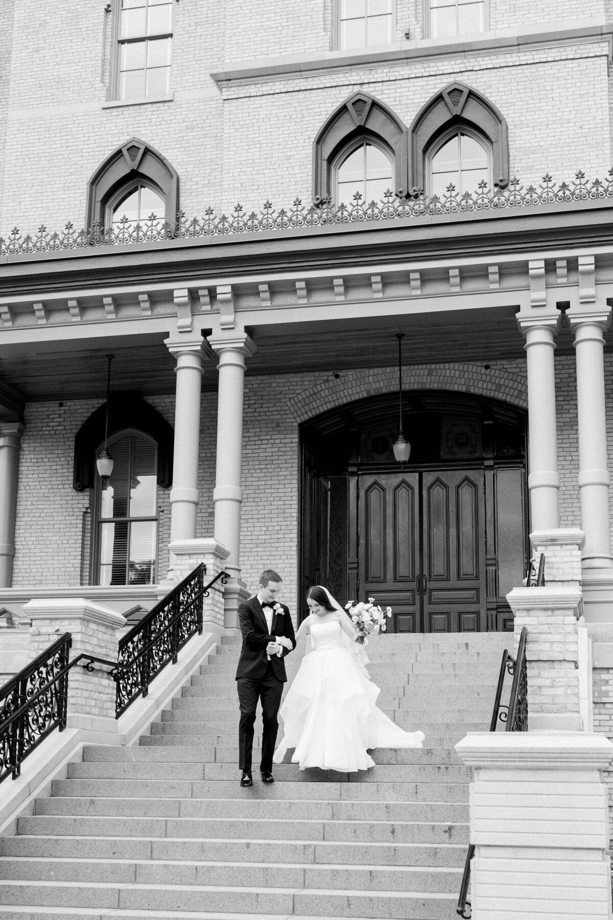 groom helping bride walk down steps in her wedding dress