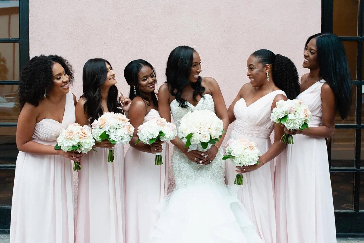 A bride and her bridesmaids smiling together.