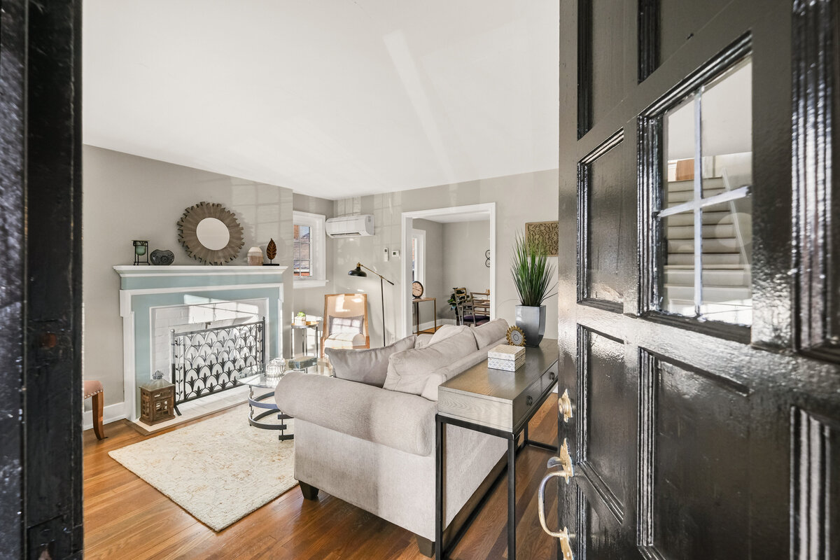 Front door opening into professionally staged living room with fireplace