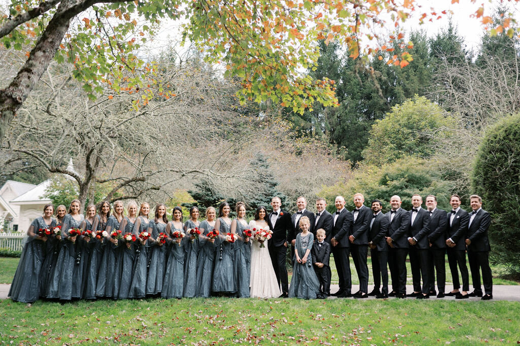 Large bridal party standing on a lawn surround by fall foliage at Old Edwards Inn in Highlands, NC. 