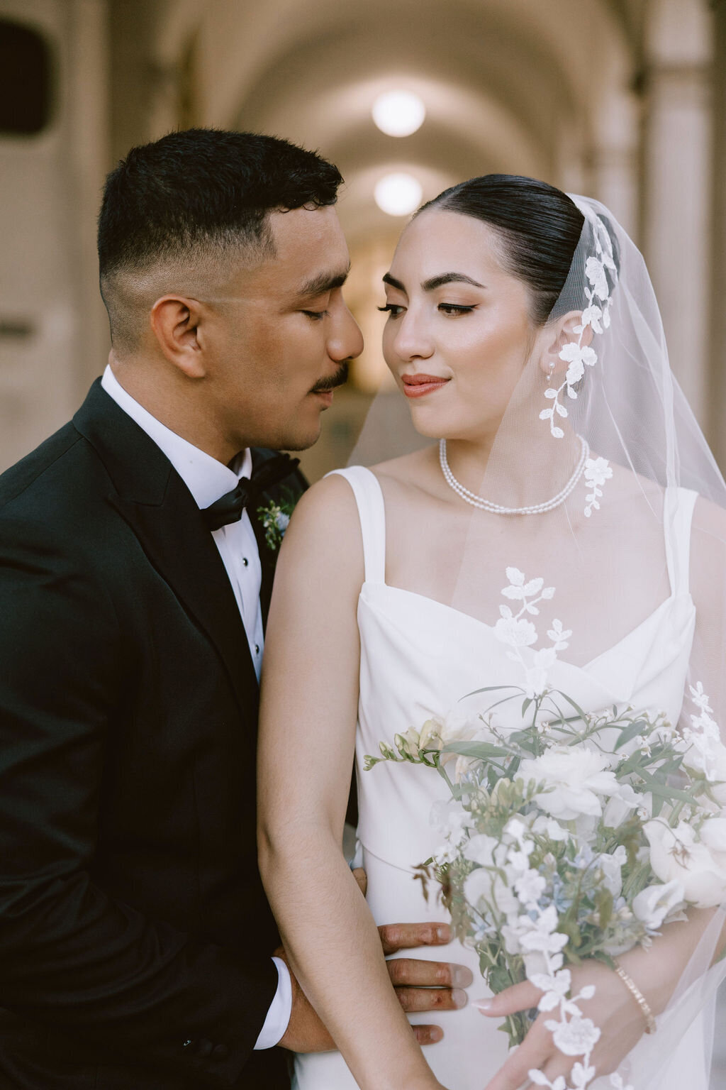 Bride and groom staring into each others eyes while he holds her waist