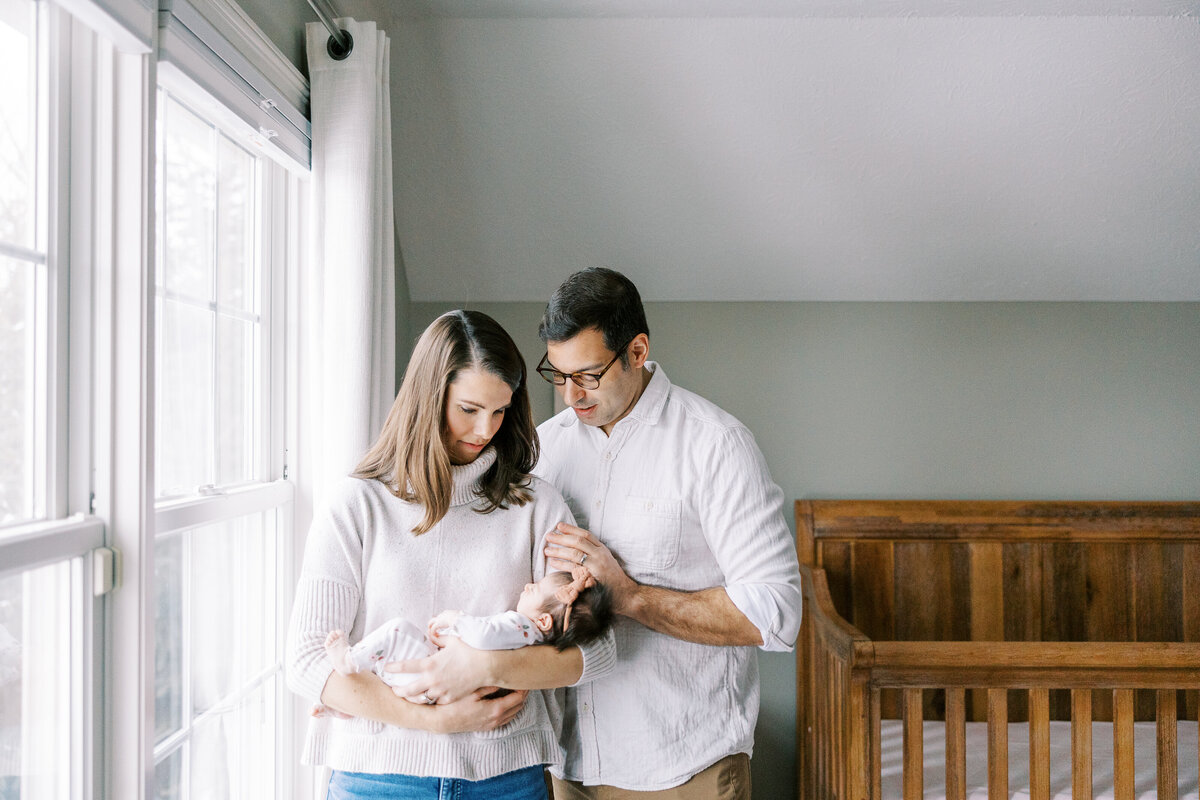 photo of mom and dad smiling at newborn baby during newborn session