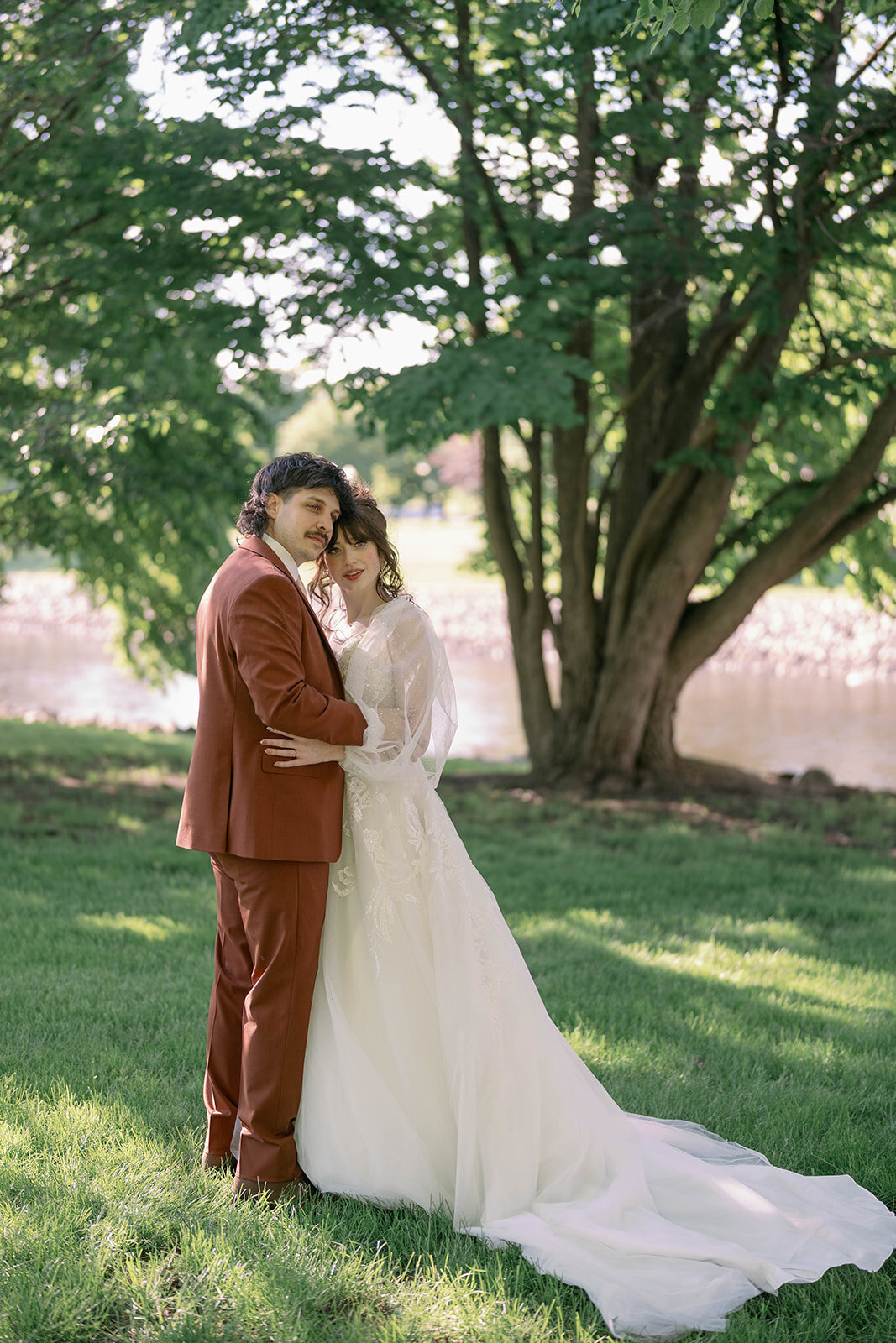 Couple standing under trees during romantic spring wedding photos in downtown Battle Creek