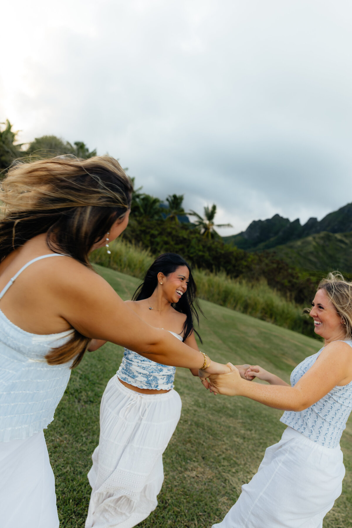 Candid photo of three best friends  spinning around together at Kualoa Regional Park