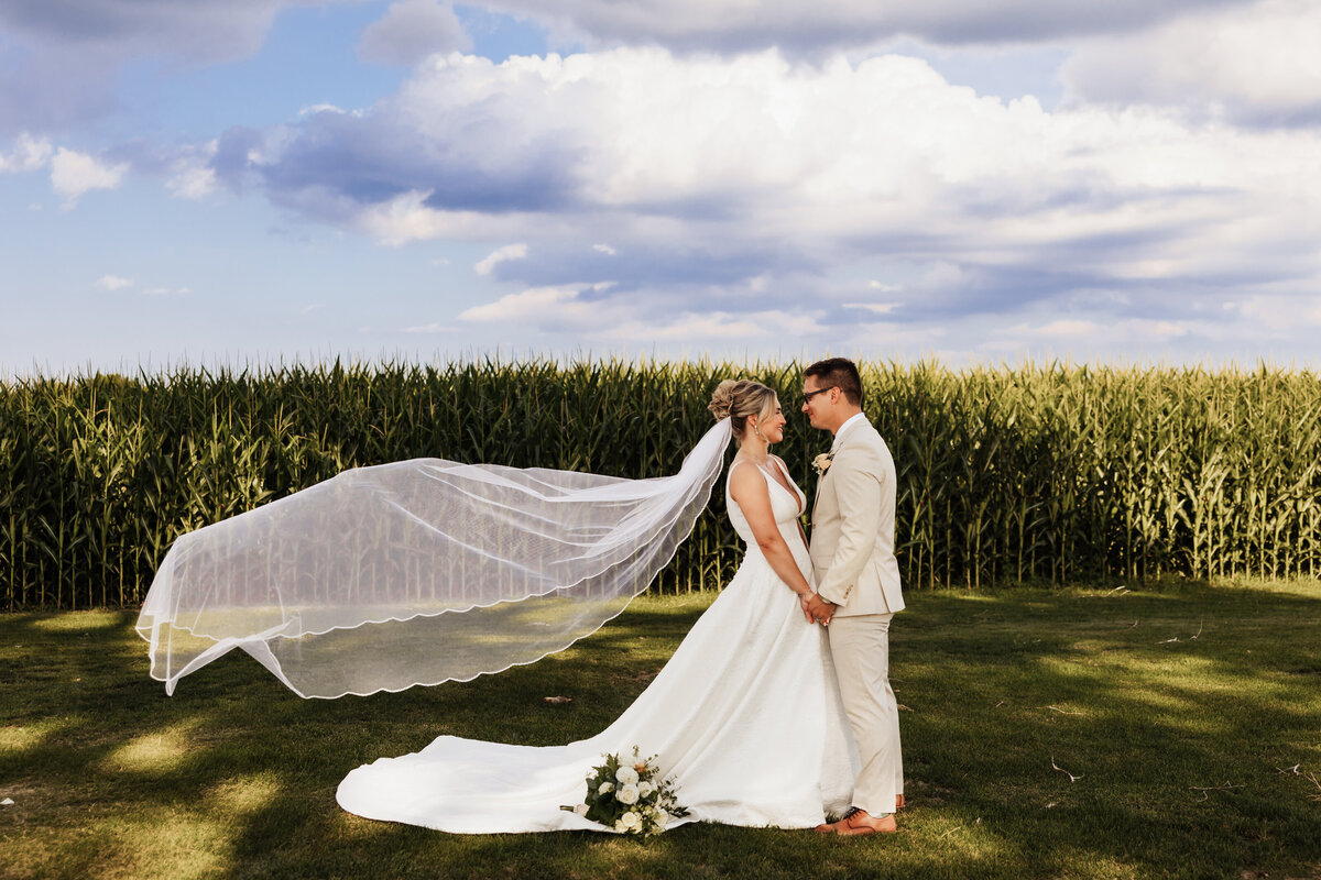 a wedding couple holds hands while her veil swoops in the wind.