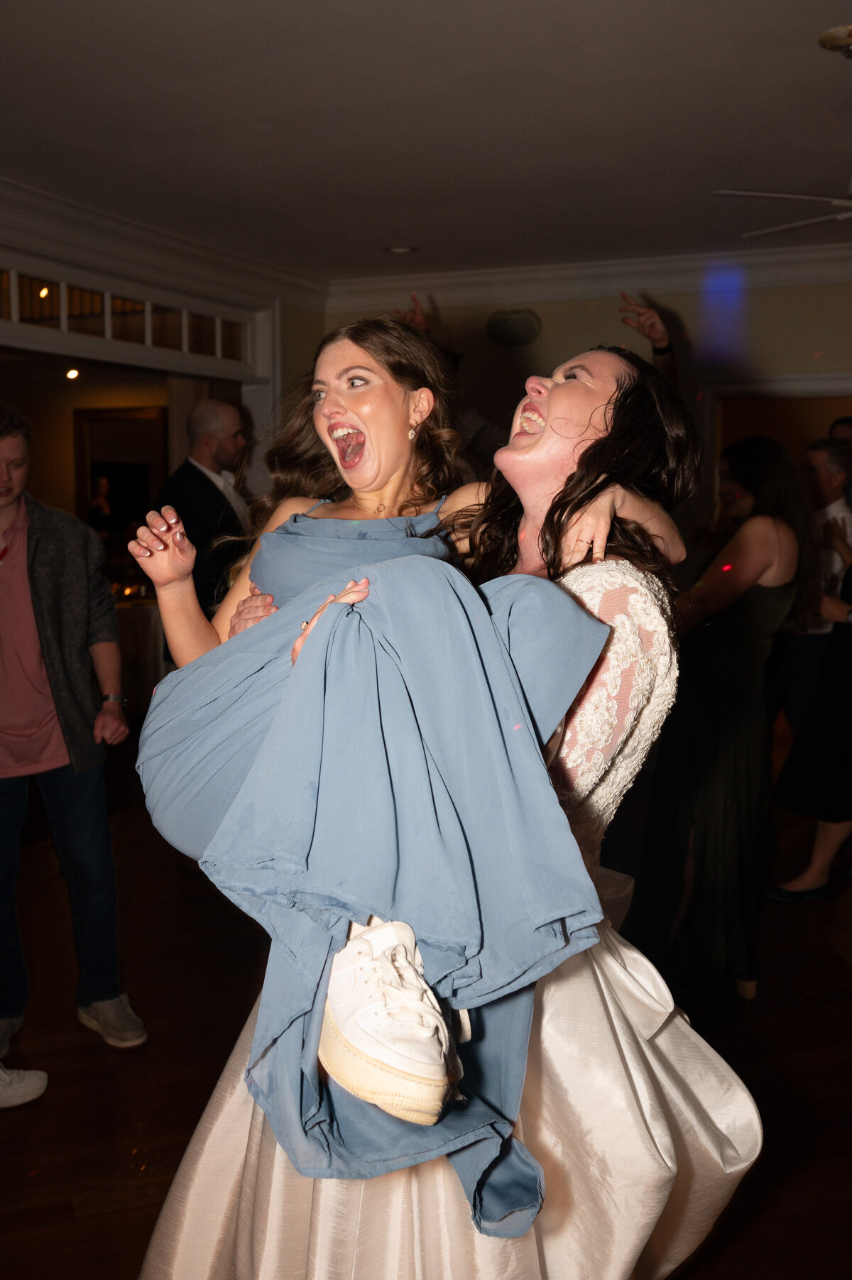 A newlywed holding a wedding guest in their arms and dancing