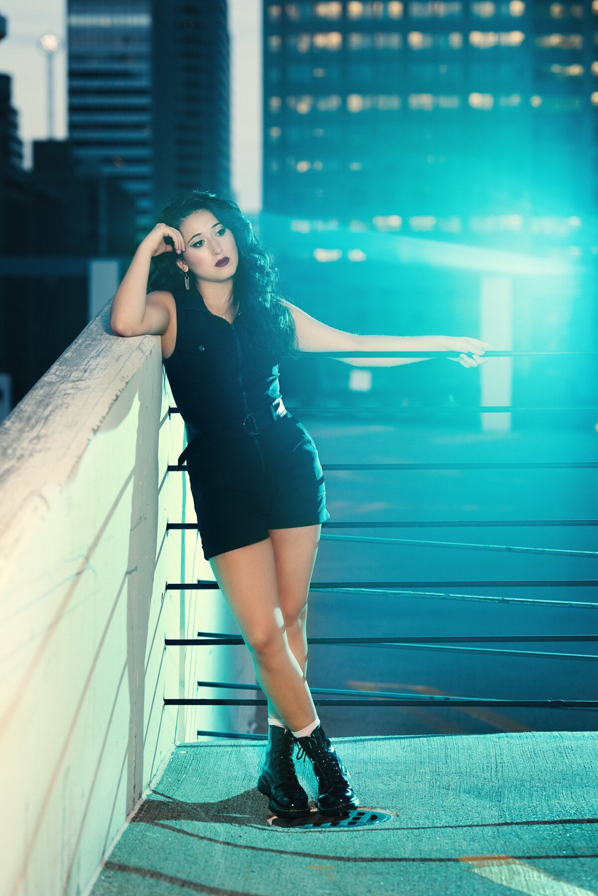senior photo of girl on parking ramp with black outfit and blue gel light