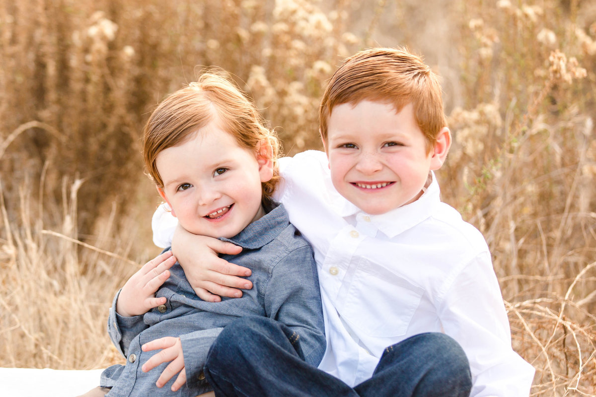 two brothers sitting in field of tall grass