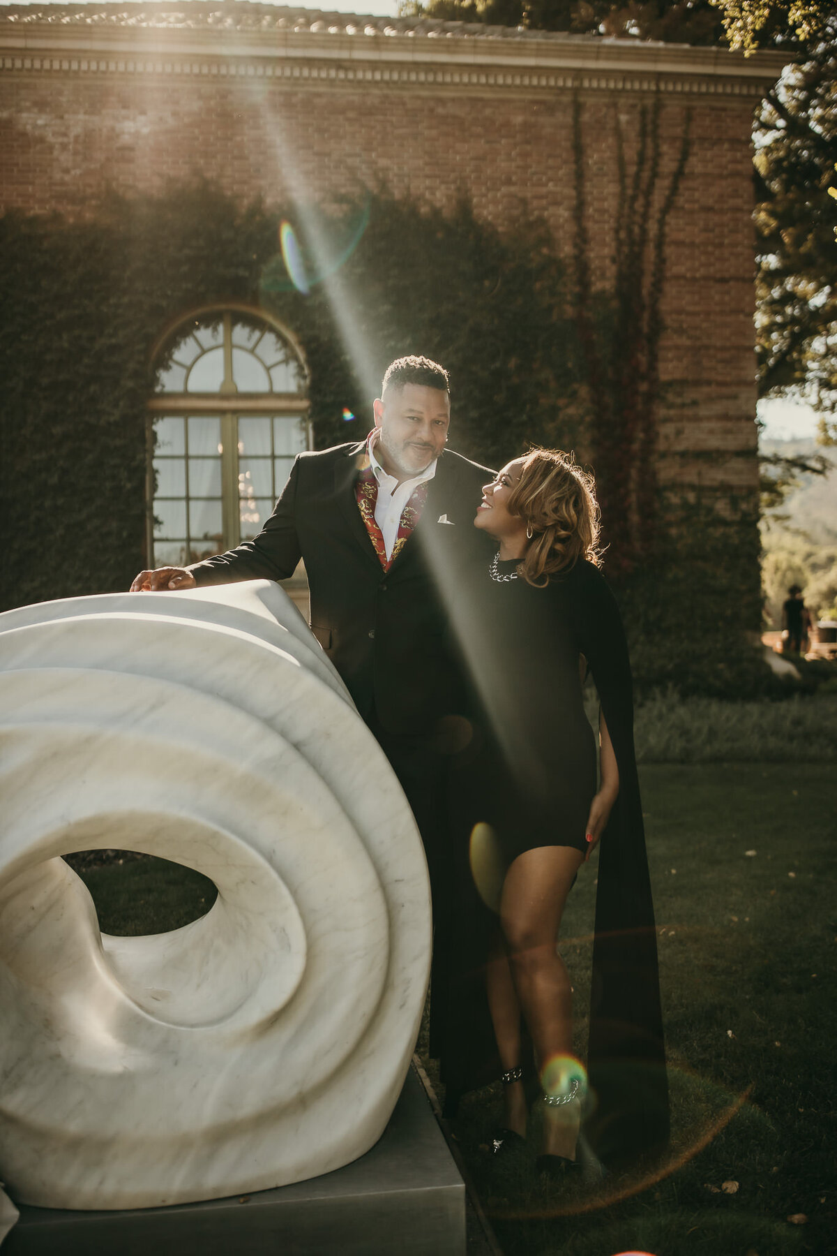 Bay Are couples photography at Filoli Gardens. Man and women in black tie formal wear standing by white marble structure.