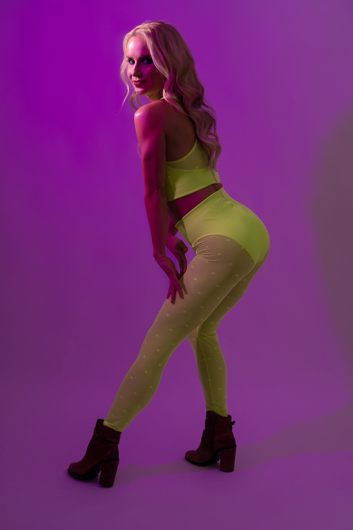 a image of a woman wearing neon leggins and boots posing to the camera