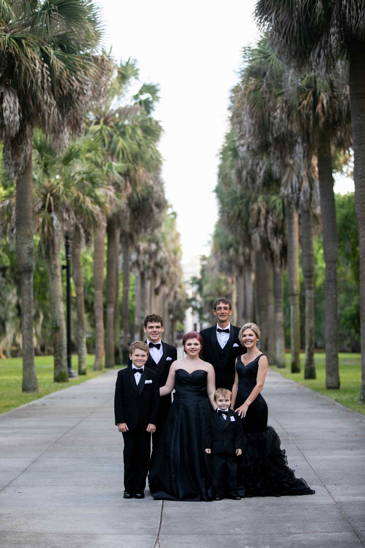 family in formal wear posed on tree lined sidewalk