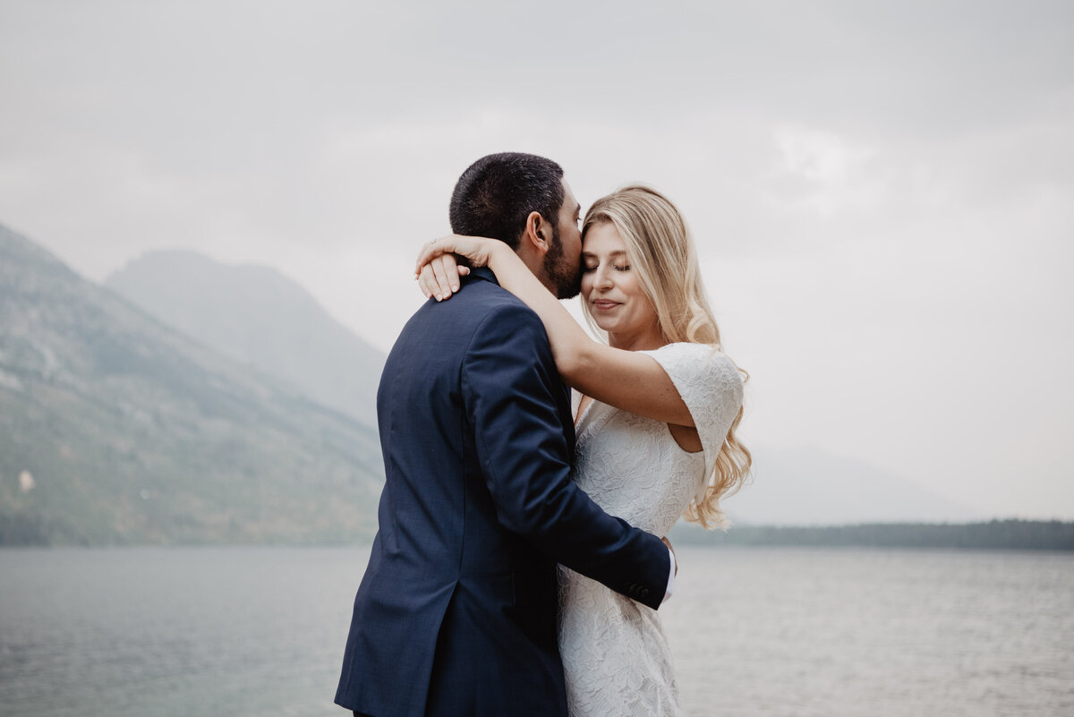 Photographers Jackson Hole capture groom kissing bride's forehead