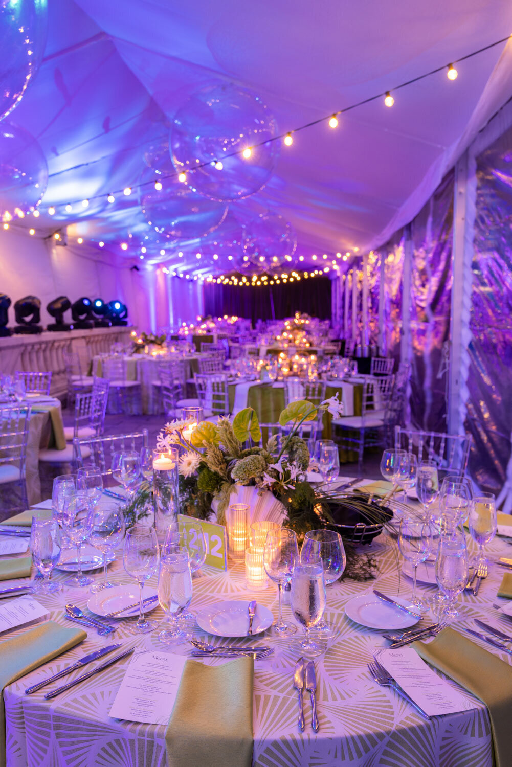 Elegant tented dinner setup with purple lighting and candles