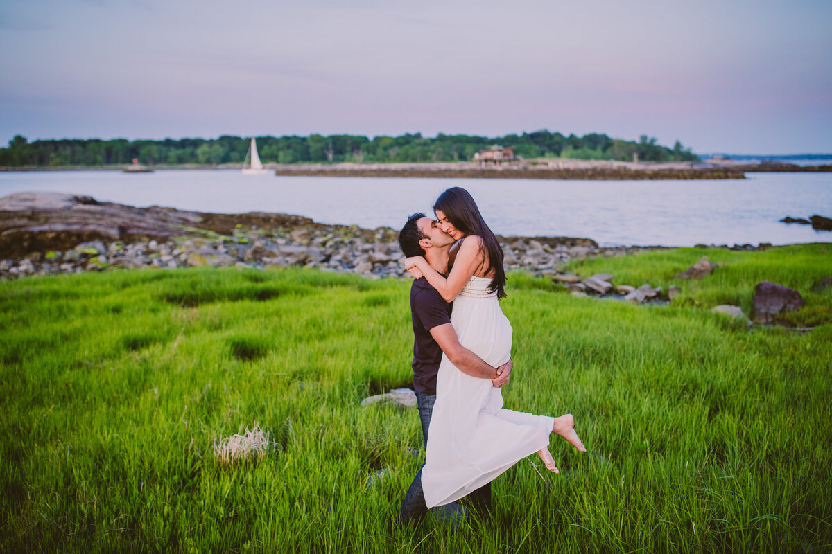 Groom picks up bride during their engagement shoot at orchard beach in the bronx ny