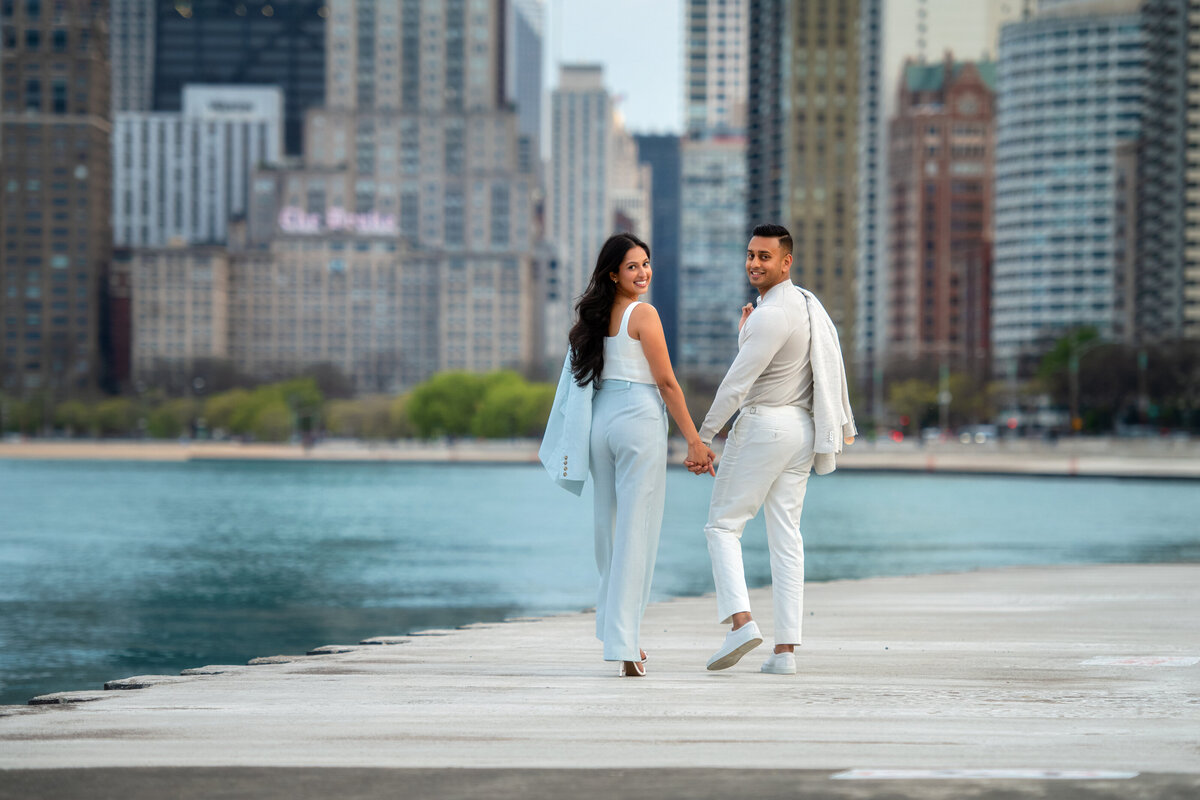 Engaged Indian couple in suits  walking  at Northe Avenue Beach in Chicago