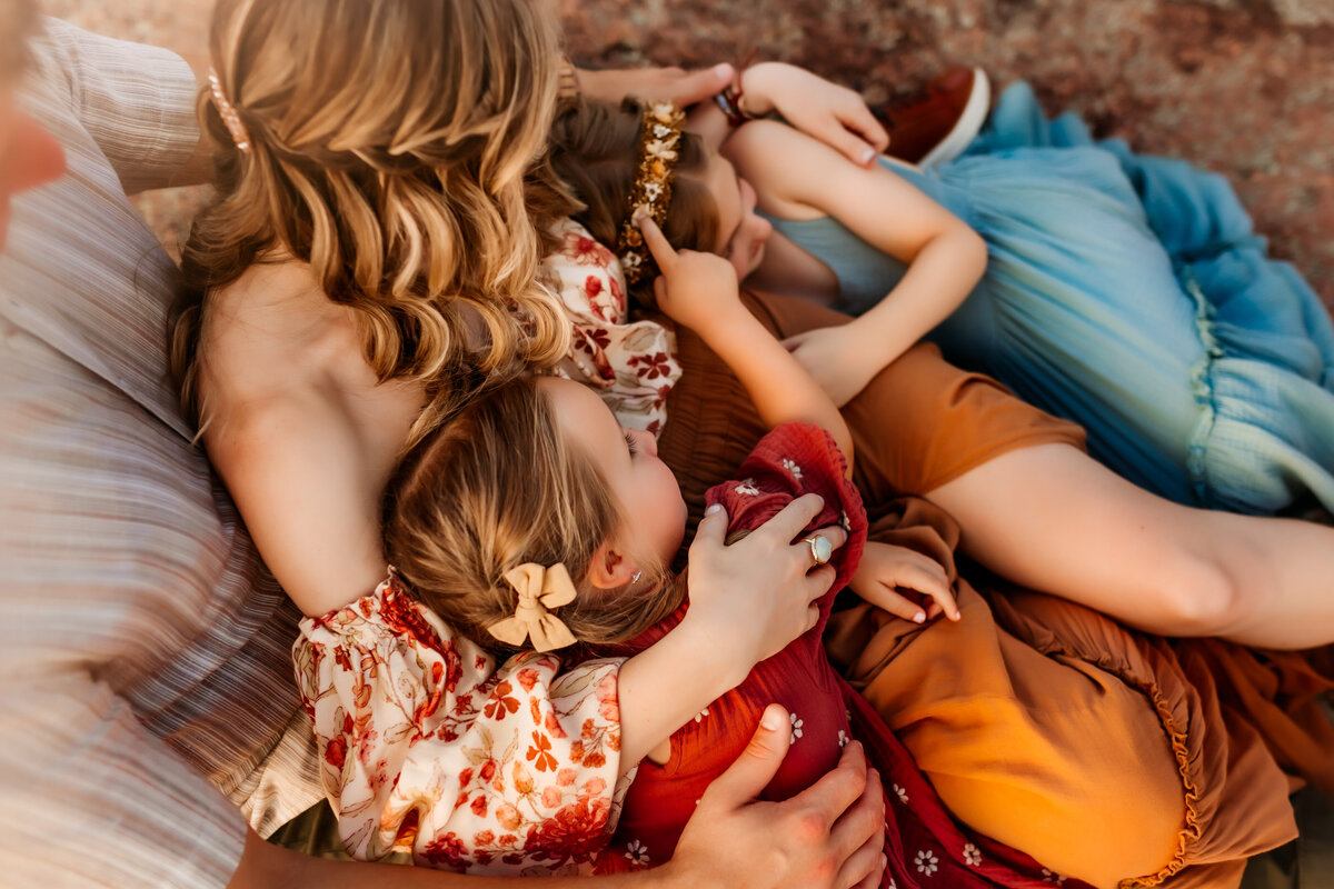 Family snuggles eachother on rock during Photoshoot in Kansas City Missouri