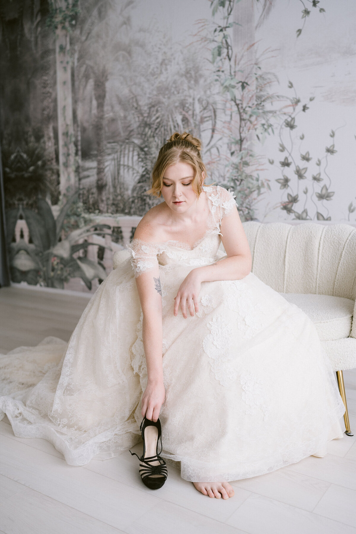 A bride fixing her high heels while getting ready at a studio