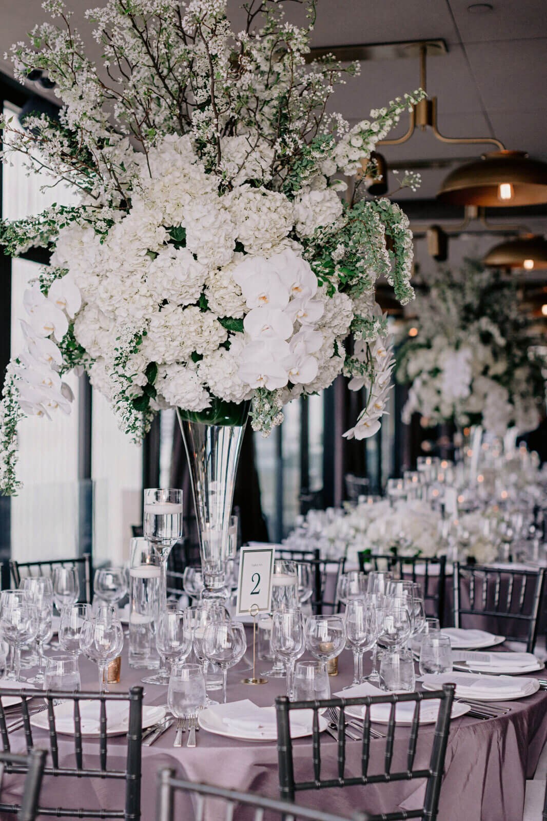 An elegant dining table with a large white flower centerpiece in The Skylark, New York. Wedding Image by Jenny Fu Studio