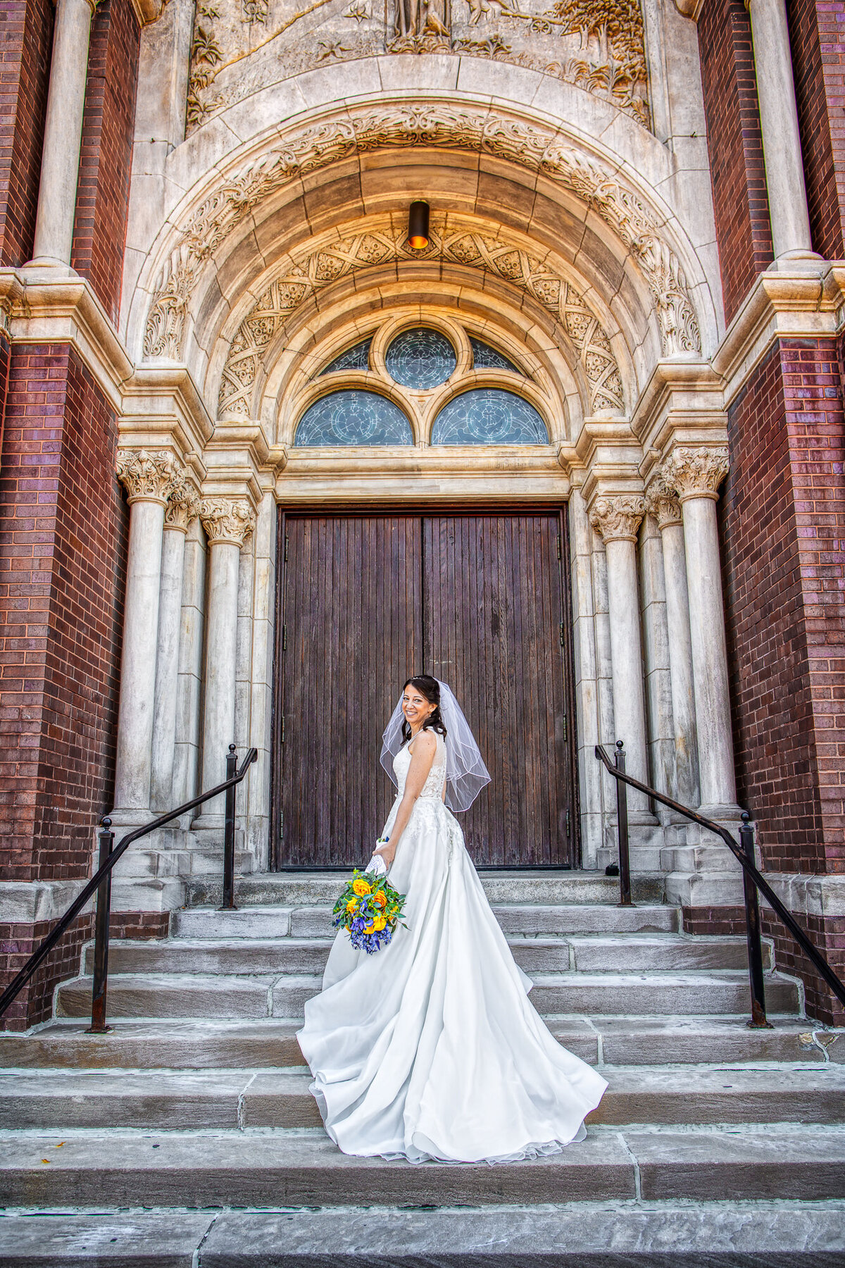 A bride with a beautiful, long dress at the staircase of her church in Chicago, IL