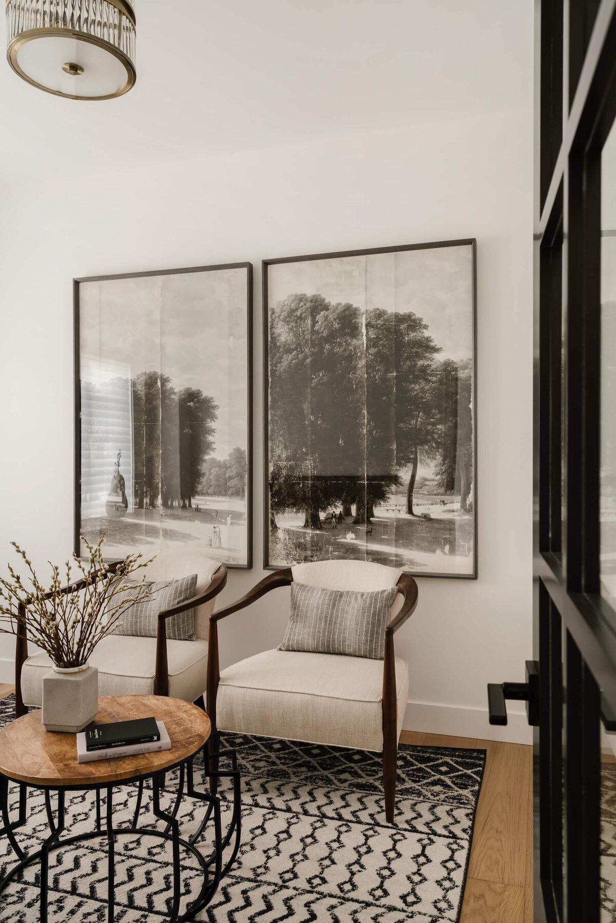 Inviting reading nook featuring oversized landscape art and comfortable upholstered chairs with natural wood arms for a warm, serene space.