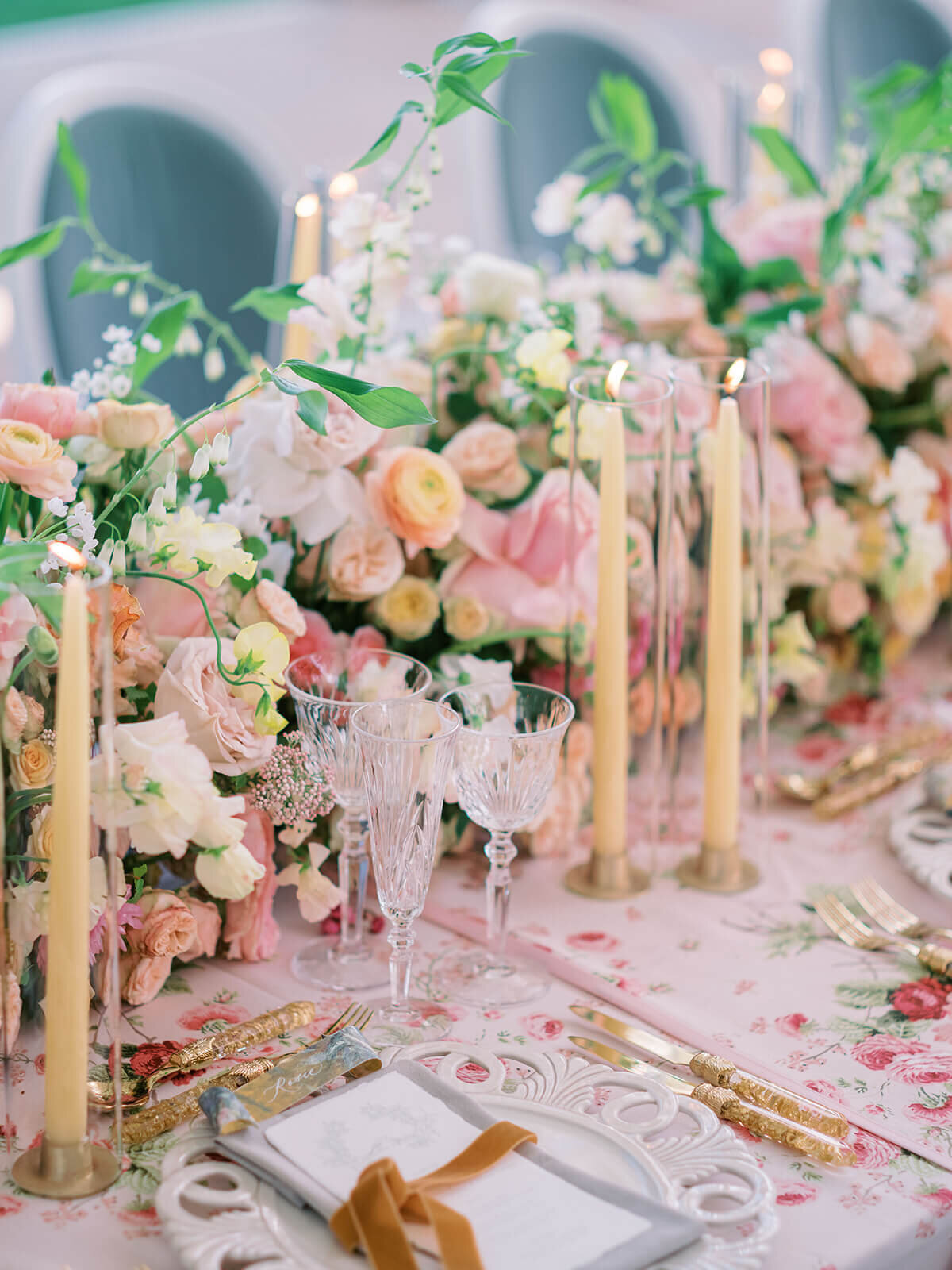 closeup of a wedding dinner table with pink floral patterned linen and pink and peach flowers contrasting with blue chairs at blenheim palace