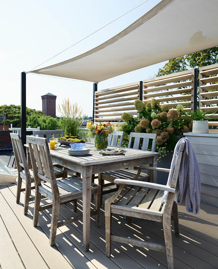 Enjoy a Boston skyline view from this rooftop deck featuring a custom trellis, sailcloth shade, and weathered teak furniture. A true city retreat. By Sarah Scales.