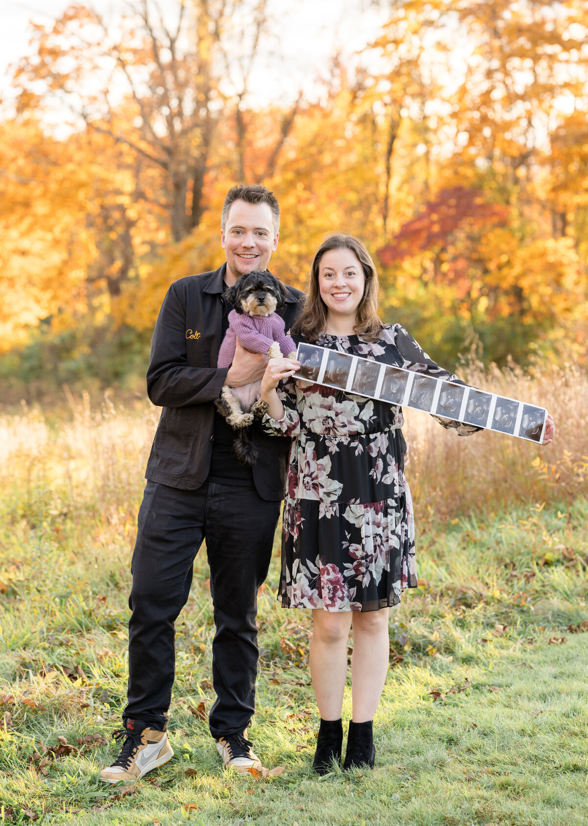 Couple announcing pregnancy with ultrasound photos in a fall photo session