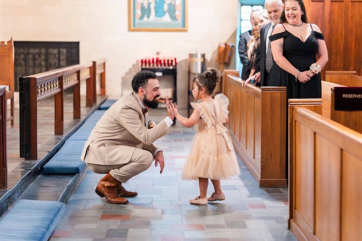Groom greeting flower girl during ceremony in Houston