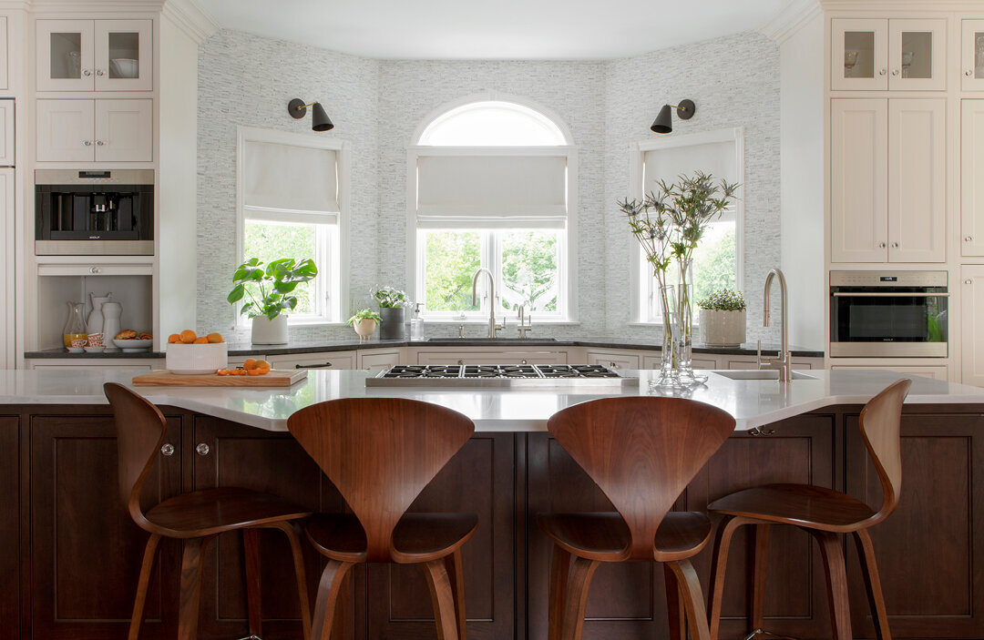 Interior design companies in Boston create a white and walnut kitchen design in Westwood, Massachusetts, with mid-century modern furniture and Ann Sacks tile.