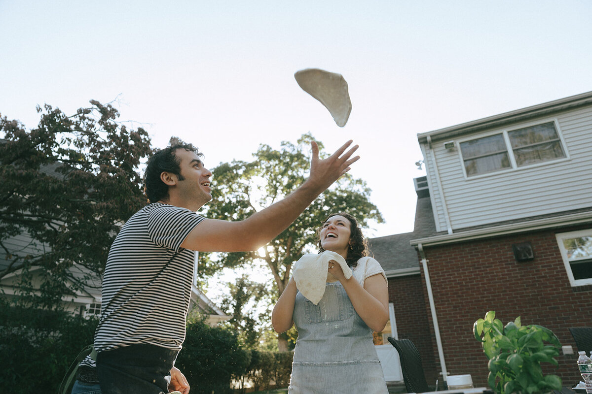 couple making pizza during at home engagement photos, captured by Elsie Goodman, an NYC engagement and couples photographer