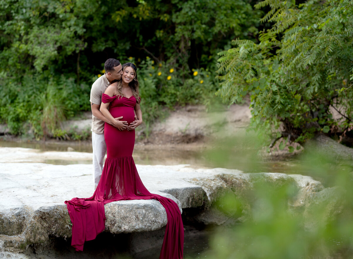 Pregnant couple giggling by the creek