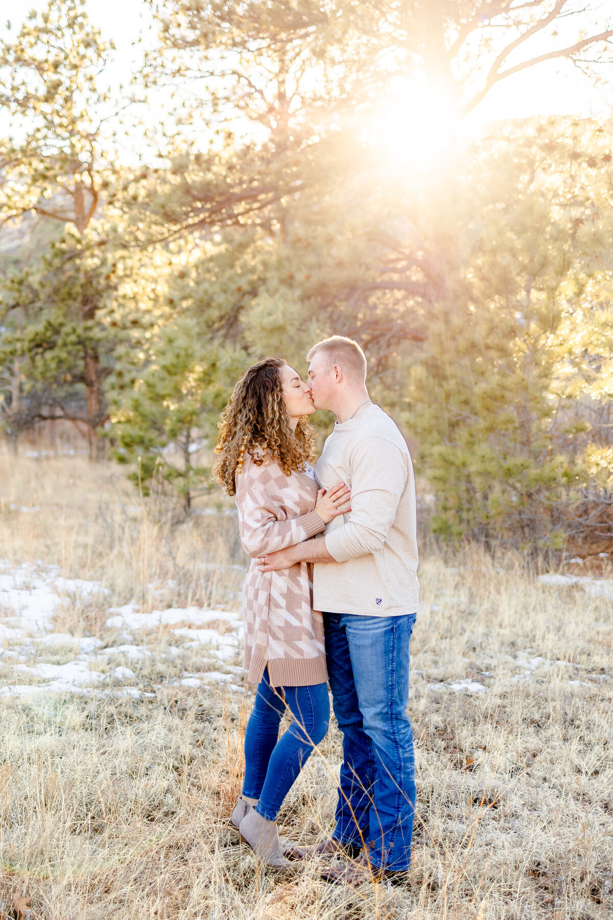 Colorado Springs Family Photographer _ Couple kissing  in field with trees and a sun flare