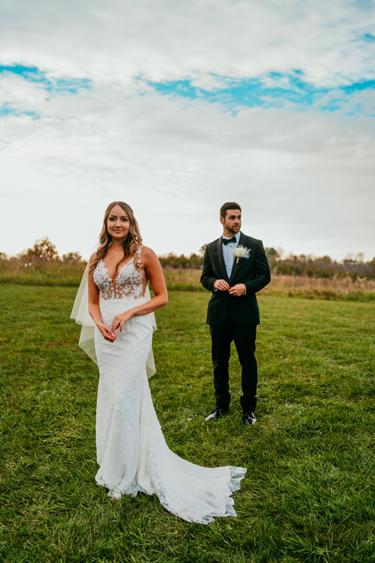 Bride and groom standing in open field during sunset elopement