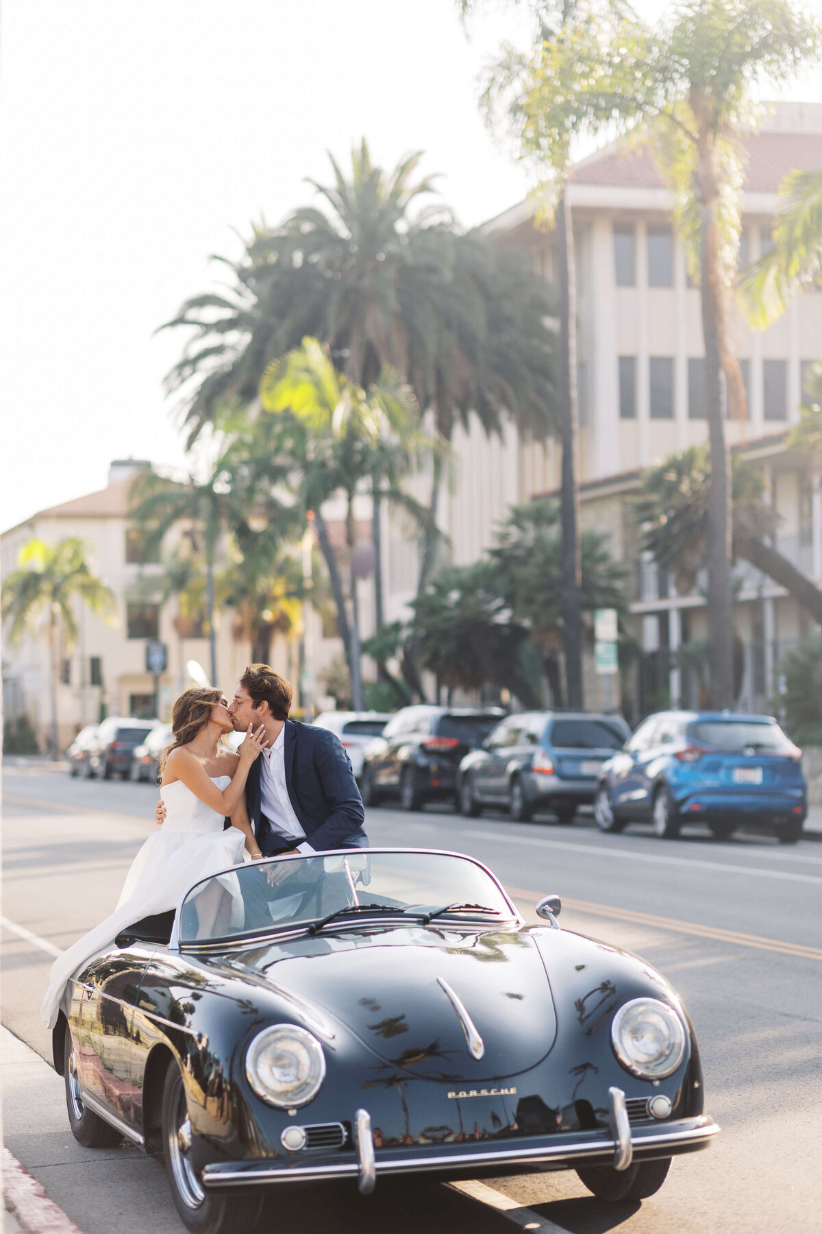 Couple kisses in the back of a vintage convertible Porsche.