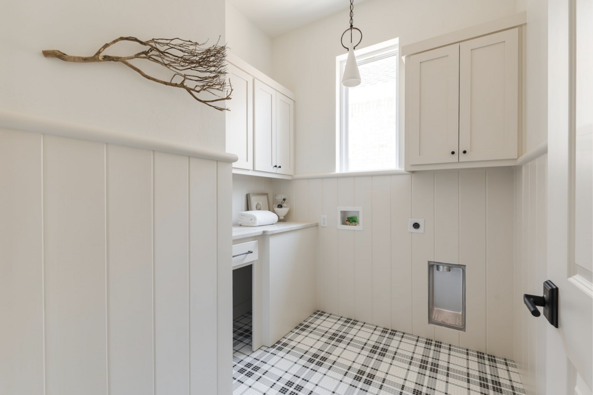 Neutral laundry room with vertical paneling, cream cabinetry, playful plaid tile flooring.