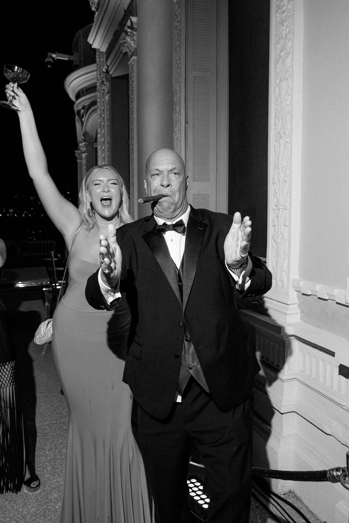 Two guests clapping during the wedding reception while smoking their cigars.