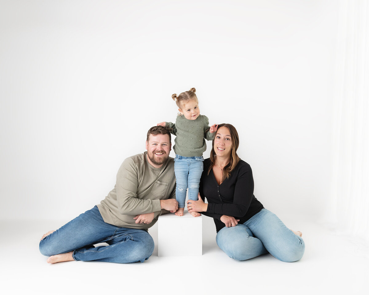 Studio family portrait with daughter standing on white cube between parents | Paris Ontario